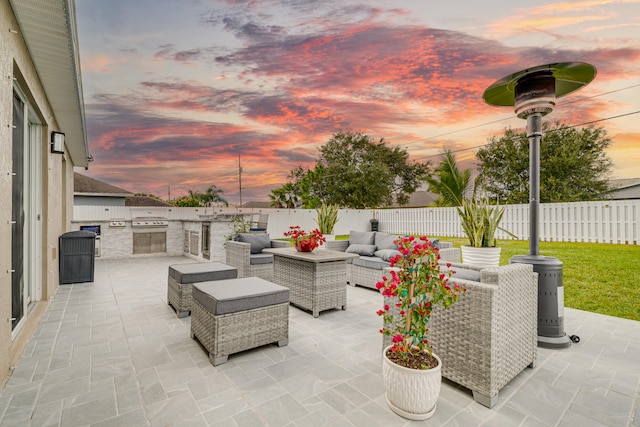 patio terrace at dusk with an outdoor hangout area and an outdoor kitchen