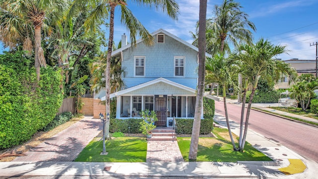 view of front of house with a sunroom and a front lawn