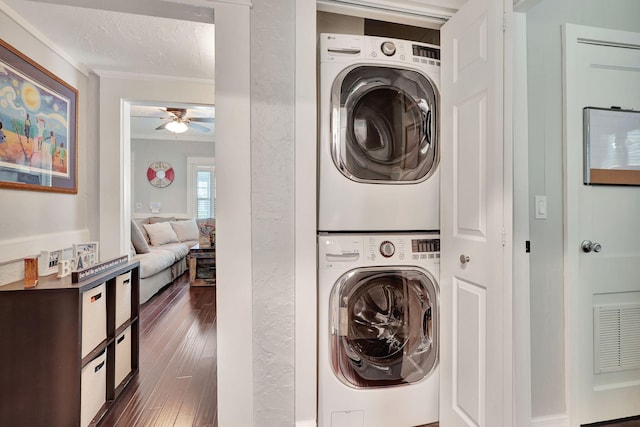 laundry area featuring ceiling fan, stacked washing maching and dryer, ornamental molding, a textured ceiling, and dark hardwood / wood-style flooring