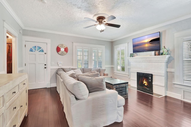 living room featuring ceiling fan, crown molding, a fireplace, and dark wood-type flooring