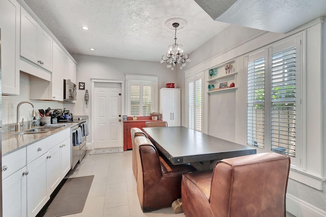 kitchen with pendant lighting, white cabinetry, sink, and appliances with stainless steel finishes