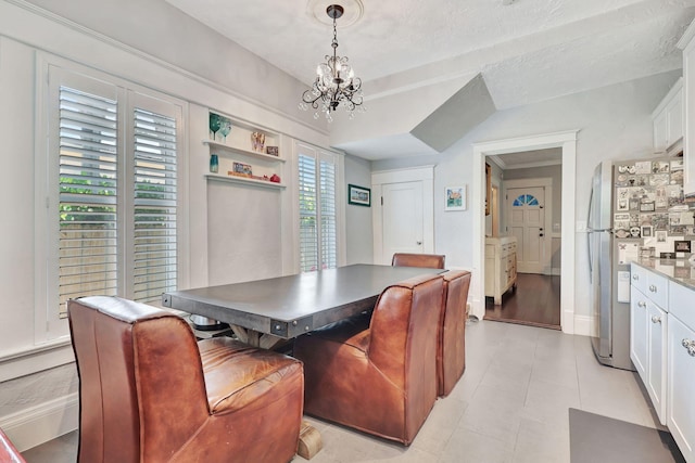 dining area with light tile patterned floors, a textured ceiling, and an inviting chandelier