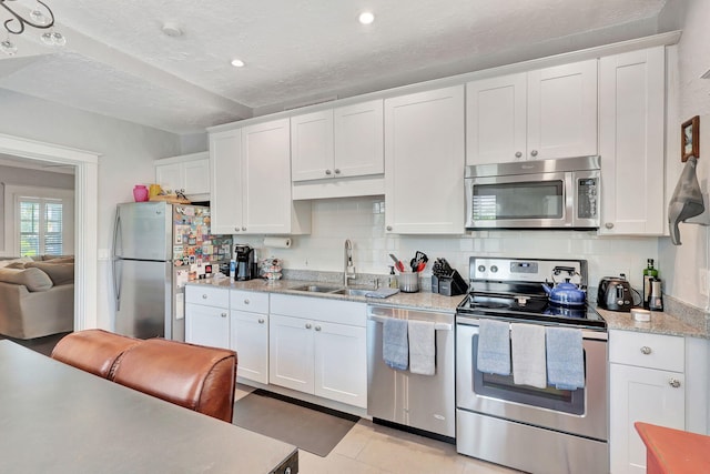 kitchen with white cabinets, backsplash, sink, and stainless steel appliances