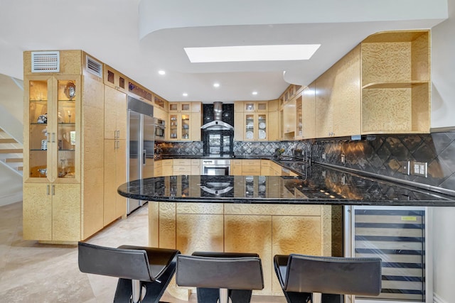 kitchen with stainless steel built in refrigerator, tasteful backsplash, kitchen peninsula, beverage cooler, and wall chimney range hood