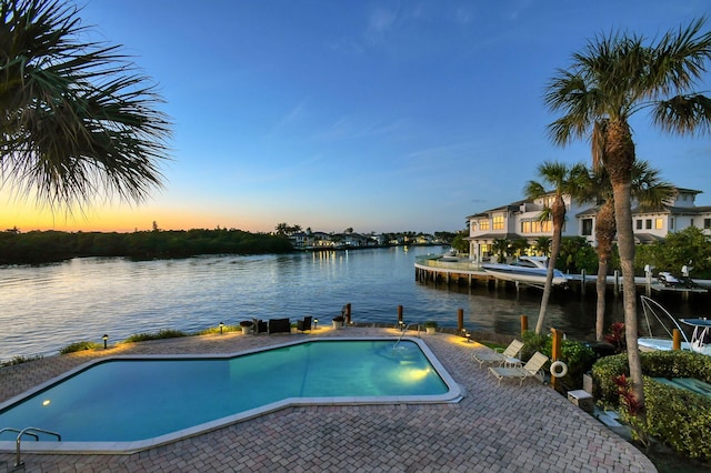 pool at dusk featuring a water view