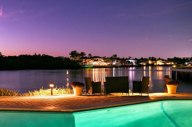 pool at dusk featuring a water view