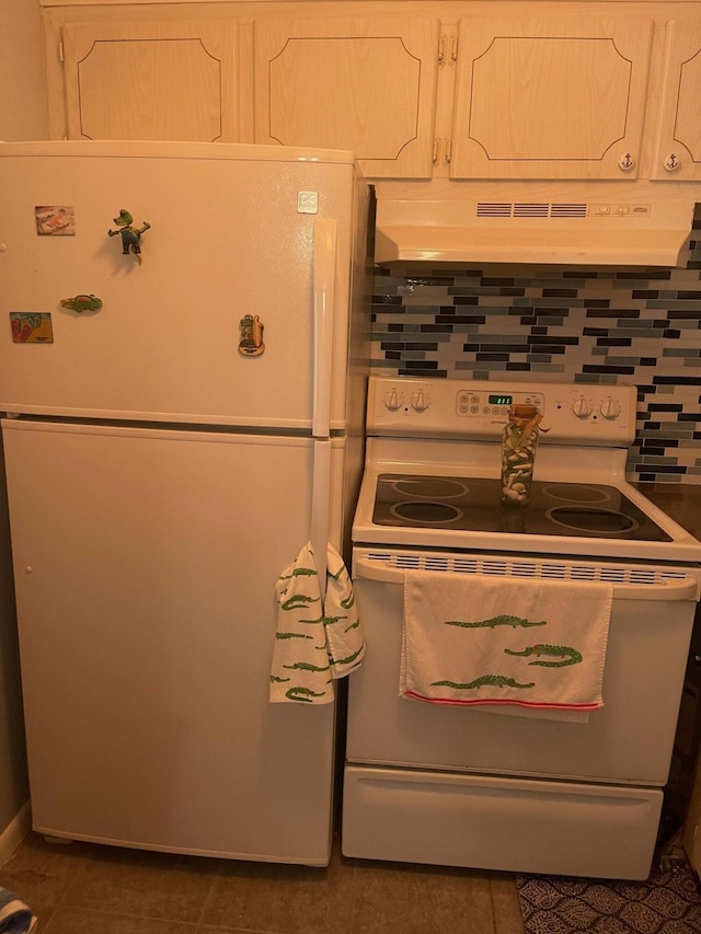 kitchen with white appliances, dark tile patterned floors, white cabinets, and extractor fan