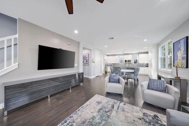 living room featuring ceiling fan and dark wood-type flooring