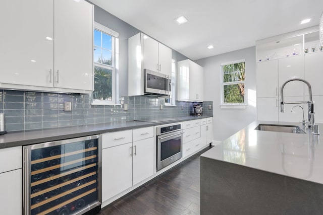 kitchen with decorative backsplash, stainless steel appliances, sink, white cabinetry, and wine cooler