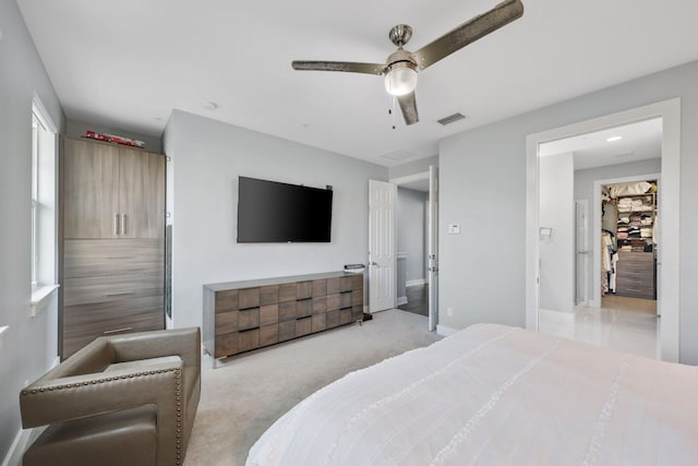 carpeted bedroom with a walk in closet and ceiling fan