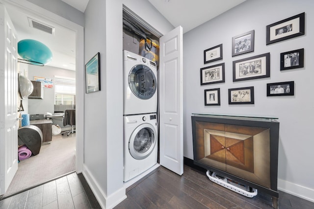 clothes washing area with dark wood-type flooring and stacked washer / drying machine