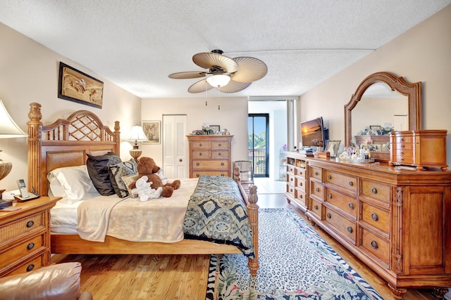 bedroom with ceiling fan, a closet, a textured ceiling, and light hardwood / wood-style flooring