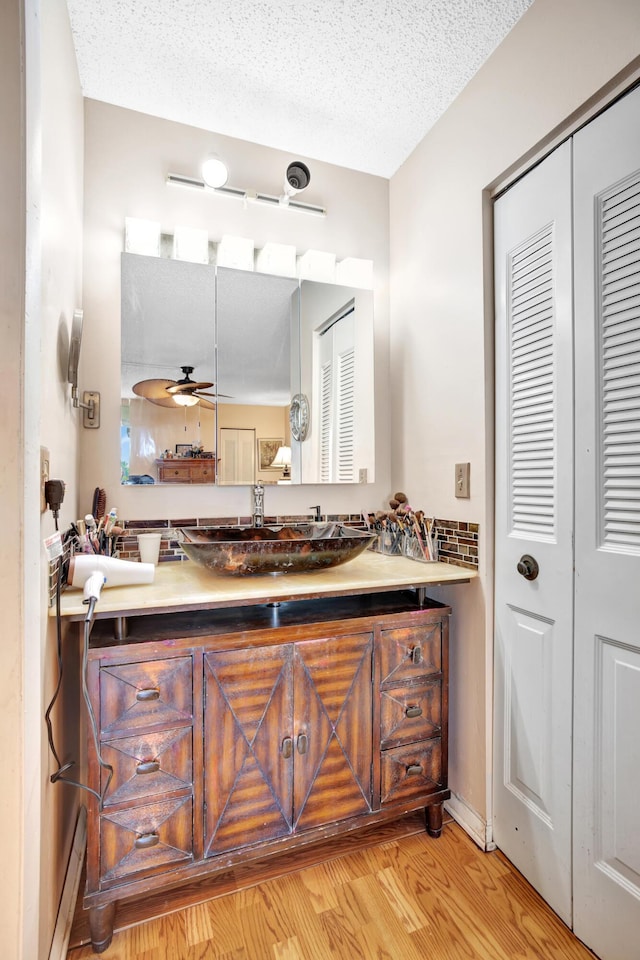 bathroom featuring ceiling fan, vanity, wood-type flooring, and a textured ceiling