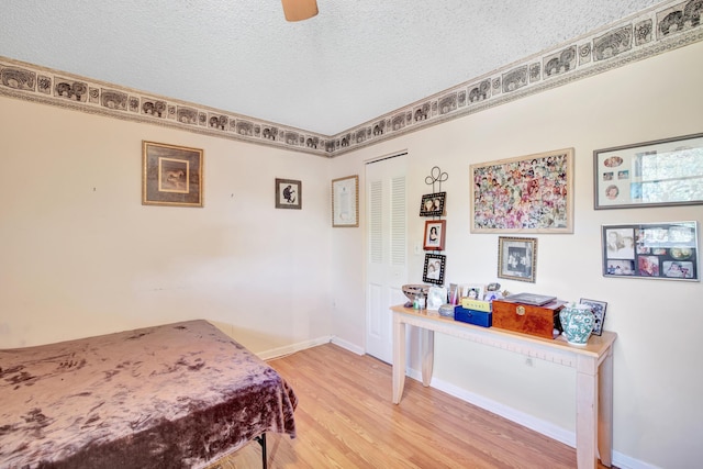 bedroom with ceiling fan, wood-type flooring, a textured ceiling, and a closet