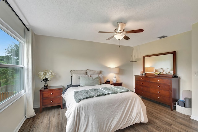 bedroom featuring ceiling fan, dark hardwood / wood-style floors, and a textured ceiling