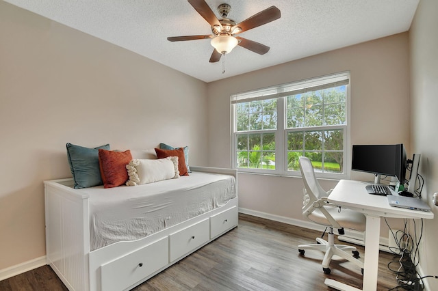 bedroom with hardwood / wood-style flooring, ceiling fan, and a textured ceiling