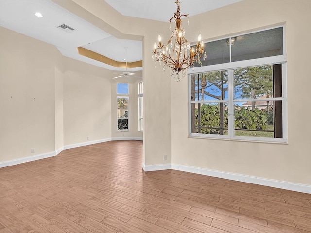 empty room with ceiling fan with notable chandelier and light wood-type flooring