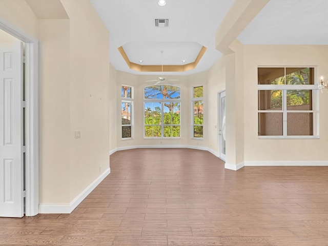 interior space featuring light hardwood / wood-style floors, a wealth of natural light, and a tray ceiling