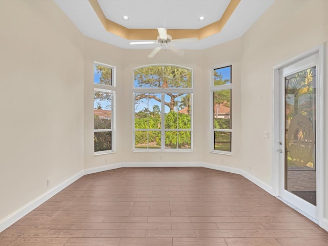 spare room featuring ceiling fan, a raised ceiling, and light hardwood / wood-style flooring