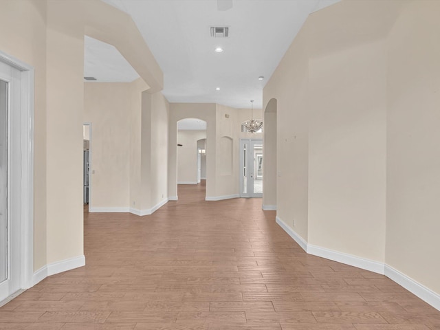 hallway with light hardwood / wood-style floors and an inviting chandelier