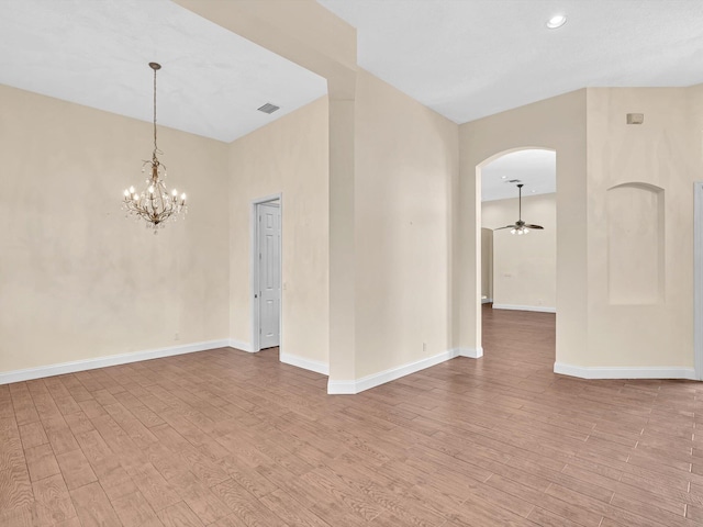 unfurnished room with ceiling fan with notable chandelier and light hardwood / wood-style flooring