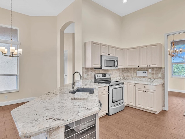 kitchen featuring kitchen peninsula, appliances with stainless steel finishes, a notable chandelier, and sink