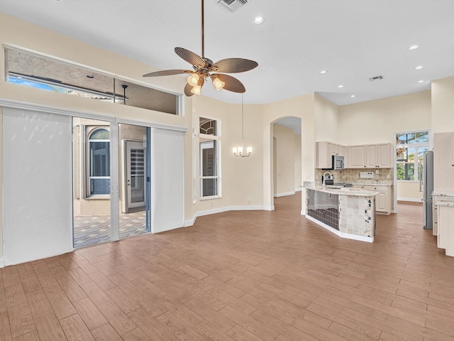 kitchen with a breakfast bar, light hardwood / wood-style flooring, stainless steel appliances, and ceiling fan with notable chandelier