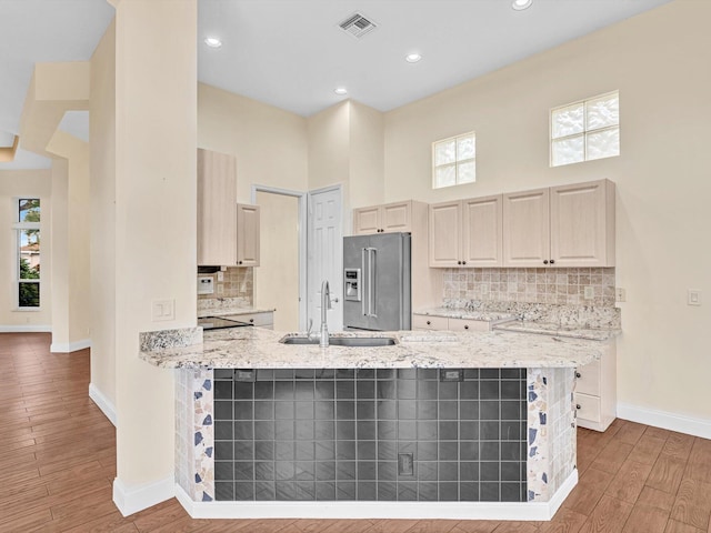 kitchen with wood-type flooring, plenty of natural light, high quality fridge, and light stone counters