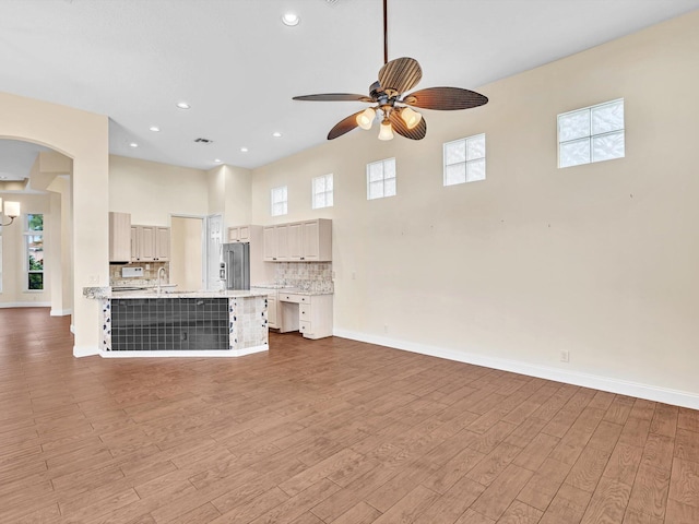 unfurnished living room with hardwood / wood-style flooring, ceiling fan, and sink