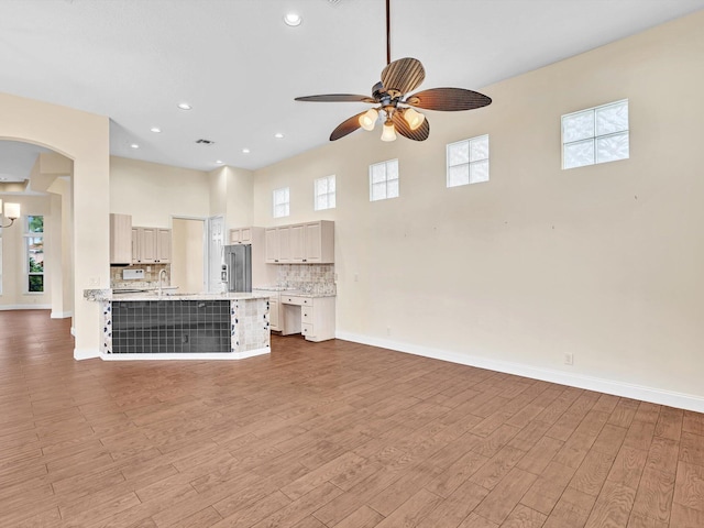 unfurnished living room featuring sink, hardwood / wood-style flooring, and ceiling fan