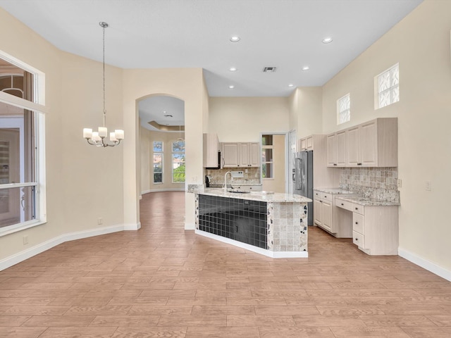 kitchen featuring pendant lighting, sink, light hardwood / wood-style flooring, light stone countertops, and decorative backsplash
