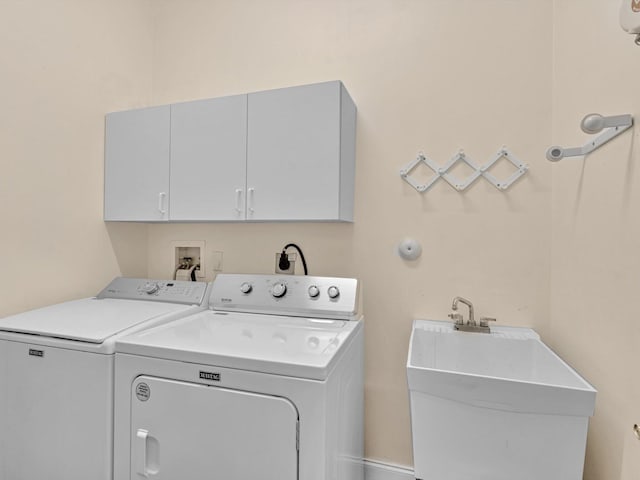 clothes washing area featuring washer and clothes dryer, sink, and cabinets