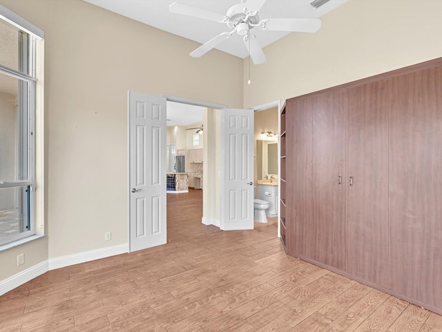 unfurnished bedroom featuring connected bathroom, light hardwood / wood-style floors, and ceiling fan