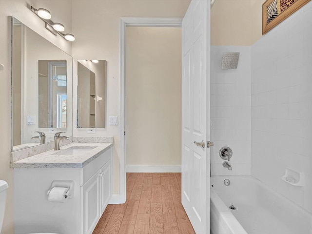 full bathroom featuring tiled shower / bath combo, wood-type flooring, vanity, and toilet