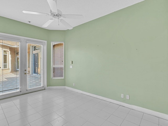 spare room with plenty of natural light, light tile patterned floors, ceiling fan, and french doors