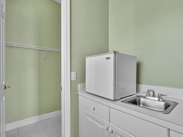 washroom with sink, light tile patterned floors, and cabinets