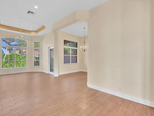 spare room with a raised ceiling and a notable chandelier