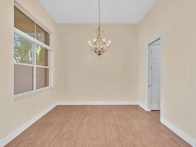 empty room with a chandelier and light wood-type flooring