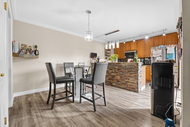 dining area featuring crown molding, track lighting, and light wood-type flooring