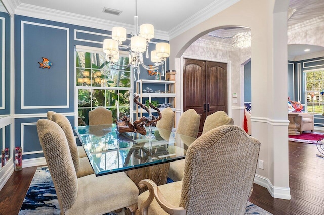 dining space featuring dark hardwood / wood-style floors, decorative columns, crown molding, and a notable chandelier