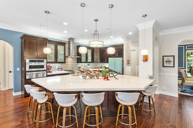 kitchen with backsplash, wall chimney exhaust hood, a large island with sink, white fridge, and oven