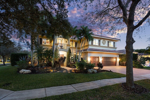 mediterranean / spanish-style house with a lawn, a balcony, and a garage