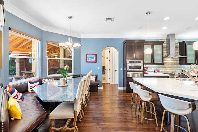 dining room with dark wood-type flooring, a notable chandelier, and ornamental molding