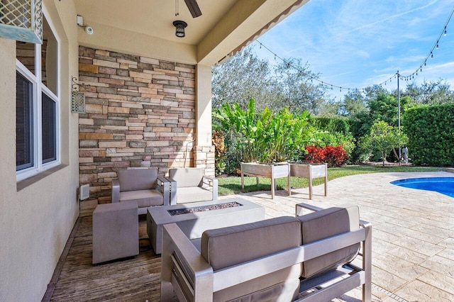 view of patio with an outdoor living space with a fire pit and ceiling fan