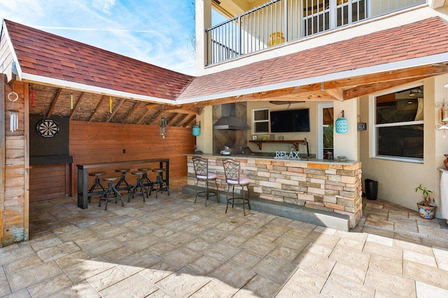 view of patio with area for grilling, a balcony, and a bar