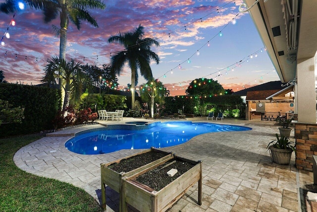 pool at dusk with a patio area and an in ground hot tub