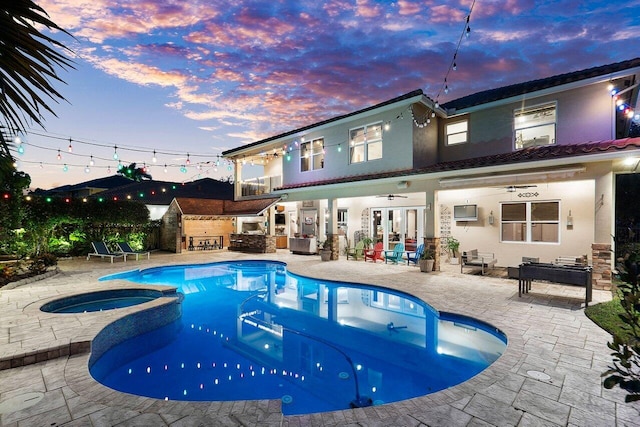 pool at dusk with area for grilling, an in ground hot tub, and a patio area