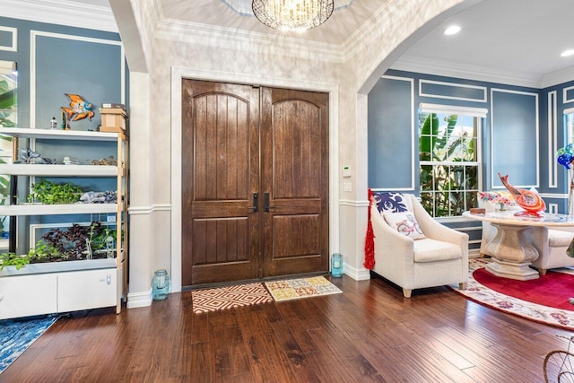 entryway featuring dark hardwood / wood-style flooring, ornamental molding, and a notable chandelier