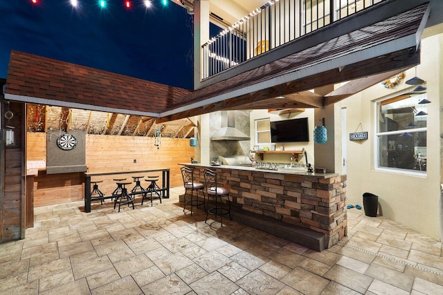 view of patio / terrace featuring an outdoor kitchen, a balcony, and a bar