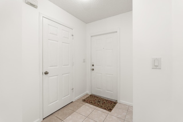 entryway featuring light tile patterned flooring and a textured ceiling